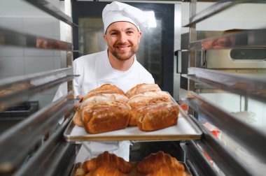 Erkek baker bir tepsi fırında ekmek fırını dükkanında holding.