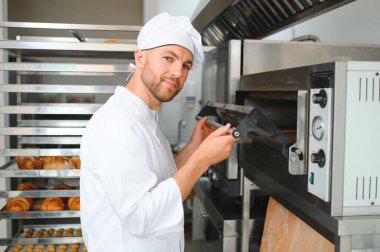 Yakışıklı baker ekmek ekmek ve fırın arka planda portresi.