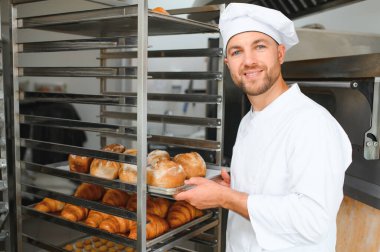 Mutlu fırıncı fırında ekmek ile tepsi nin yanında duran.