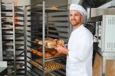 Erkek baker bir tepsi fırında ekmek fırını dükkanında holding.