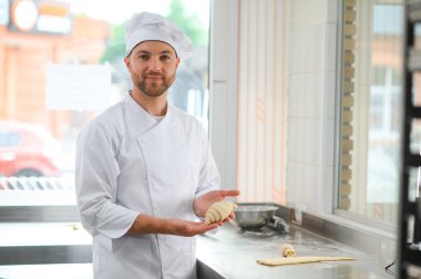 Erkek bir fırıncı fırın mutfağında kruvasan yapıyor..