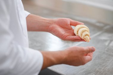 Erkek bir fırıncı fırın mutfağında kruvasan yapıyor..