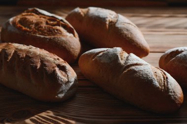 Yuvarlak ekmek yakın plan. Fırın raflarında altın hamurlu taze ekşi ekmek. Lezzetli ekmekle birlikte fırın içeriği. Hamur işleri.