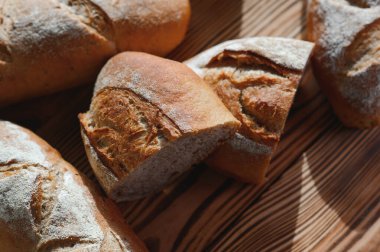 Fırın raflarında taze pişmiş ekmek. Parlak ışıkta ekmek çeşitliliği. Tahta raflarda altın hamurlu ekmek. Ekmek çeşitleri..