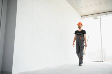 Beyaz duvar boyarken boya silindiri tutan ve yenileme yapan adamın portresi.