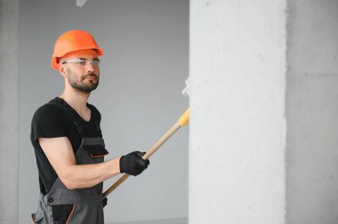 Beyaz duvar boyarken boya silindiri tutan ve yenileme yapan adamın portresi.