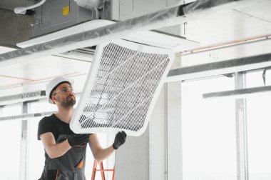 Teknisyen modern bir dairede klima sistemi temizliyor..