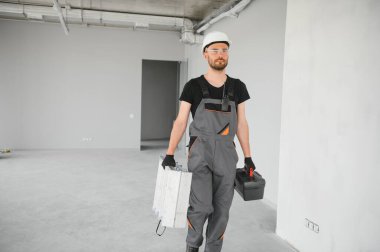 İnşaat alanında kaskı olan sevimli beyaz sakallı inşaat işçisi..