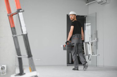 İnşaat alanında kaskı olan sevimli beyaz sakallı inşaat işçisi..