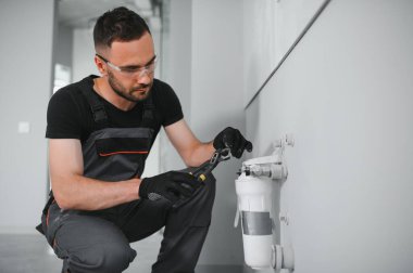 Tesisatçı su filtresi kurar ya da değiştirir. Yerleştirme su filtresi. Tamirci mutfağa su filtresi koyuyor. Ters osmoz su arıtma sisteminin kurulumu