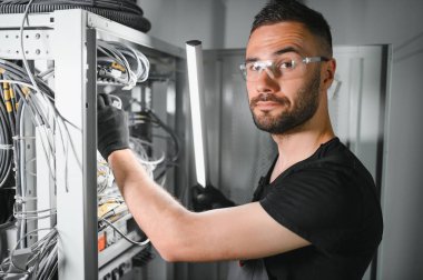 Tamirci meşgul ve sunucu odasında internet cihazları ve kablolarla çalışıyor..