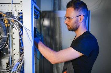 Tamirci meşgul ve sunucu odasında internet cihazları ve kablolarla çalışıyor..