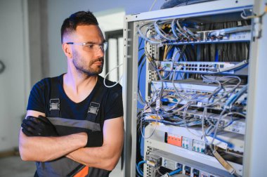 Bir teknisyen veri merkezinde sunucu ekipmanlarıyla çalışıyor. Bir adam sunucu odasında kabloları değiştiriyor..