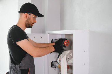 İşçi yangın söndürücüyü ve yangın hortumunu bina koridoruna yerleştirir veya denetler..