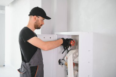 İşçi yangın söndürücüyü ve yangın hortumunu bina koridoruna yerleştirir veya denetler..