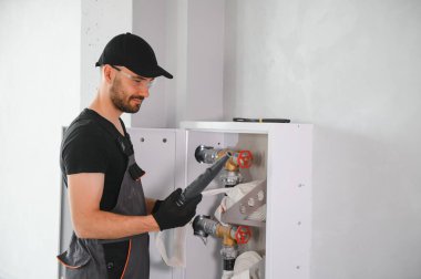 İşçi yangın söndürücüyü ve yangın hortumunu bina koridoruna yerleştirir veya denetler..