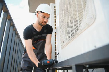 Teknisyen havalandırma ya da hava pompası üzerinde çalışıyor. HVAC servisi, bakım ve onarım.