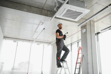 Teknisyen modern bir dairede klima sistemi temizliyor..