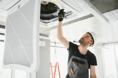 Teknisyen modern bir dairede klima sistemi temizliyor..