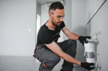 Su filtreleme sistemi kurulurken pense kullanan genç adam.
