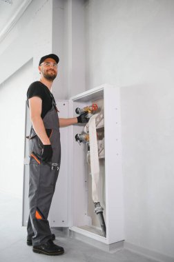 İşçi yangın söndürücüyü ve yangın hortumunu bina koridoruna yerleştirir veya denetler..