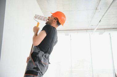 Komik ve neşeli işçi duvarları boyamak için bir silindir içinde şarkı söylüyor..