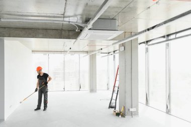 Adam duvarı boyuyor. DIY onarımı. Ressam tekerleği duvarın yanında tutuyor..