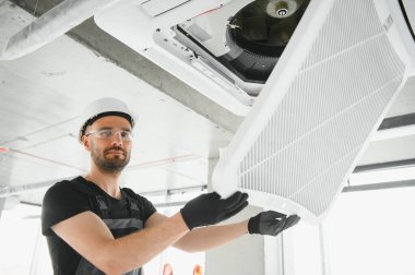 Teknisyen modern bir dairede klima sistemi temizliyor..