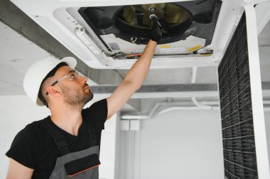 Teknisyen modern bir dairede klima sistemi temizliyor..