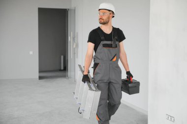 İnşaat alanında kaskı olan sevimli beyaz sakallı inşaat işçisi..