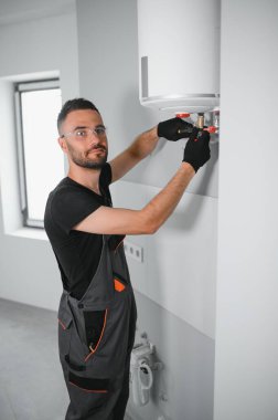 Profesyonel tesisatçı kazan ve boruları kontrol ediyor..