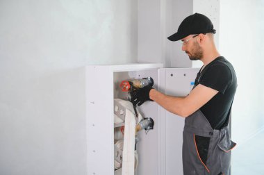 İşçi yangın söndürücüyü ve yangın hortumunu bina koridoruna yerleştirir veya denetler..