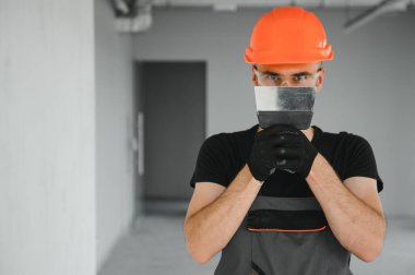 Alçıpan işçisi ya da sıva ve alçı kullanarak duvarlara alçı bant yapıştıran bir adam. Beyaz şapka, iş eldiveni ve güvenlik gözlüğü takıyordu. Kopyalama alanı olan resim