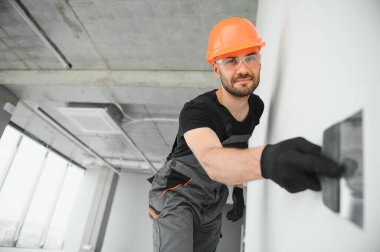 Profesyonel işçi duvarları macun bıçağıyla sıva yapıyor..