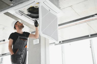 Teknisyen modern bir dairede klima sistemi temizliyor..