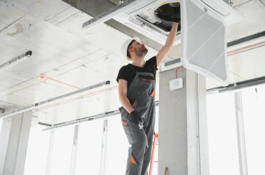 Teknisyen modern bir dairede klima sistemi temizliyor..
