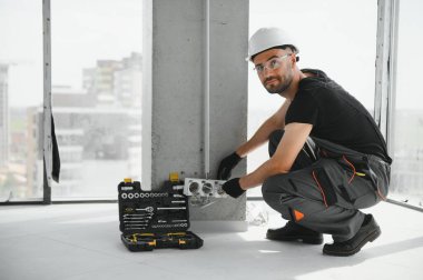 Elektrikçi soket kutularını duvara yerleştirir ve üzerine macun koyar..