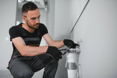 Su filtreleme sistemi kurulurken pense kullanan genç adam.