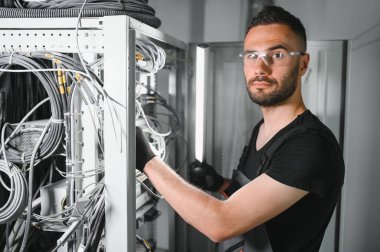 Tamirci meşgul ve sunucu odasında internet cihazları ve kablolarla çalışıyor..