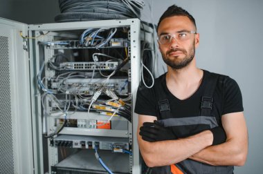 Tamirci meşgul ve sunucu odasında internet cihazları ve kablolarla çalışıyor..