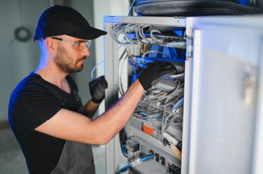 Bir teknisyen veri merkezinde sunucu ekipmanlarıyla çalışıyor. Bir adam sunucu odasında kabloları değiştiriyor..