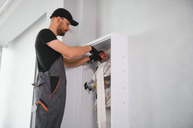 İşçi yangın söndürücüyü ve yangın hortumunu bina koridoruna yerleştirir veya denetler..