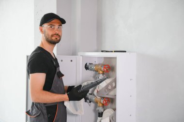 İşçi yangın söndürücüyü ve yangın hortumunu bina koridoruna yerleştirir veya denetler..