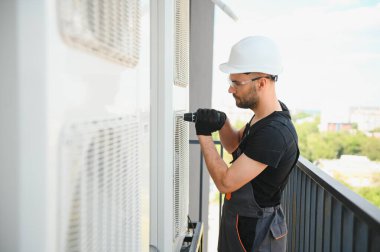 Genç bir tamirci dışarıdaki bir klimayı kontrol ediyor..