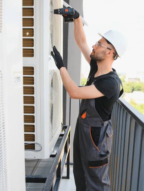 Teknisyen havalandırma ya da hava pompası üzerinde çalışıyor. HVAC servisi, bakım ve onarım.