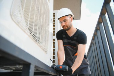 Genç bir tamirci dışarıdaki bir klimayı kontrol ediyor..