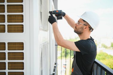 Teknisyen havalandırma ya da hava pompası üzerinde çalışıyor. HVAC servisi, bakım ve onarım.