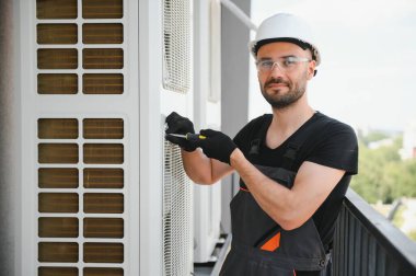 Teknisyen havalandırma ya da hava pompası üzerinde çalışıyor. HVAC servisi, bakım ve onarım.