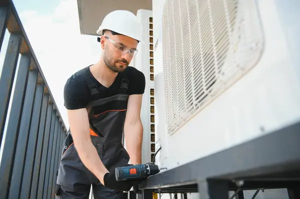 Teknisyen havalandırma ya da hava pompası üzerinde çalışıyor. HVAC servisi, bakım ve onarım.