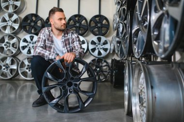 Adam araba dükkanında yeni alaşım tekerlekleri seçiyor..